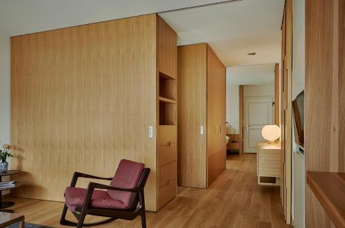 a living room with a chair and a bedroom at Bellevue Parkhotel & Spa - Relais & Châteaux in Adelboden