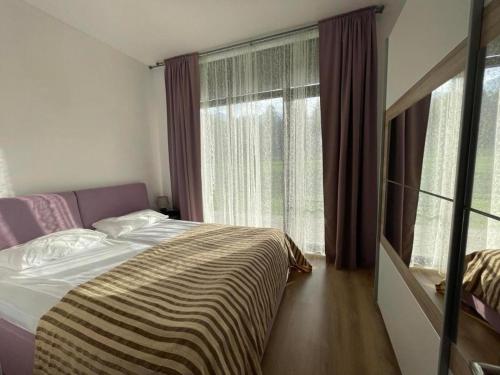 a bedroom with a bed and a large window at Charming comfortable apartment at Cornelia Deluxe Residence with free pool and SPA in Razlog