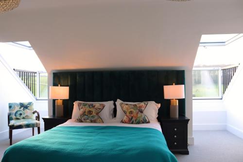 a bedroom with a green bed with two pillows at Leafield House Nables Farm in Chippenham