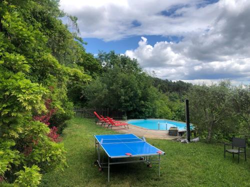 une table de ping-pong bleue dans l'herbe à côté d'une piscine dans l'établissement Le Relais des Bouziges, à Sanilhac