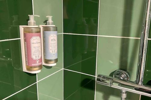 two bottles ofodorizers in a green tiled bathroom at Le cocon d'Huguette, St Denis, Paris in Saint-Denis