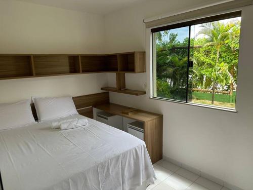 ein Schlafzimmer mit einem weißen Bett und einem Fenster in der Unterkunft Genipabu Club House Guarajuba Camaçari-Ba in Camaçari