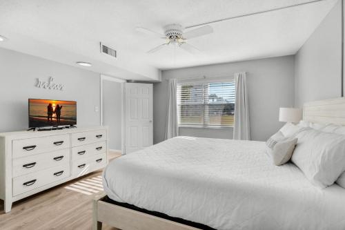 a white bedroom with a bed and a television at El Matador- Beachside Haven 210 in Fort Walton Beach