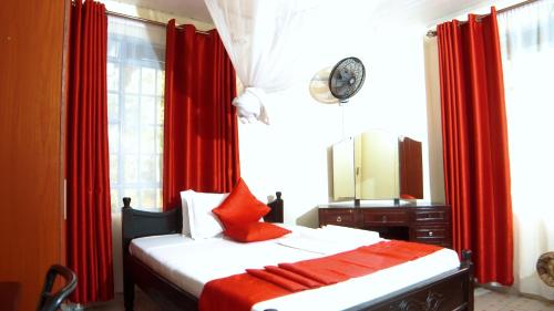 Schlafzimmer mit einem Bett mit roten Vorhängen und einem Spiegel in der Unterkunft Kisumu Boutique Hotel in Maragoli