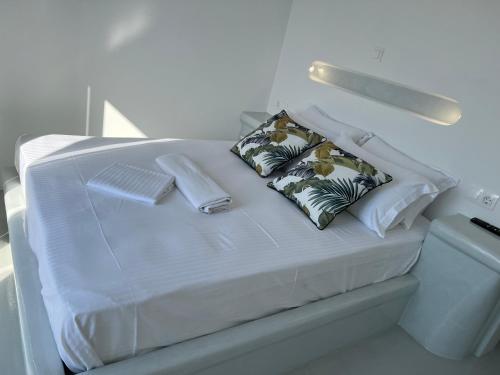 a white bed with two pillows on top of it at Alexandra’s studios in Iraklia