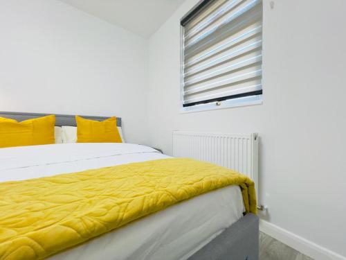 a bedroom with a bed with yellow sheets and a window at Ensuite Luxury Bedroom In Purfleet in Purfleet