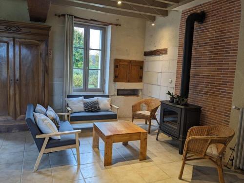 a living room with a couch and a stove at Maison dans belle longère - La Serrerie in Thenay