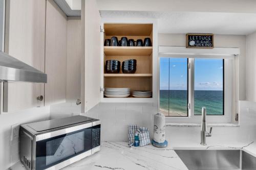 eine Küche mit einer Spüle, einer Mikrowelle und einem Fenster in der Unterkunft Shoreline Towers 2086 in Destin