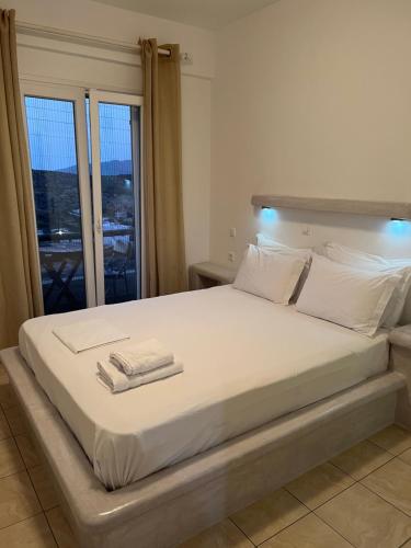 a bedroom with a large white bed with towels on it at Alexandra’s studios in Iraklia