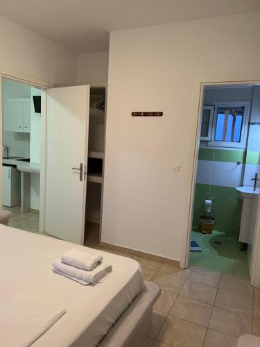 a white room with a bed and a bathroom at Alexandra’s studios in Iraklia