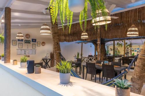 a dining room with palm trees and potted plants at Three Hearts in Fulhadhoo