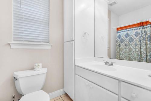 Un baño con inodoro, lavabo y espejo. en Destiny Beach Villas #11A- Beach Oasis, en Destin