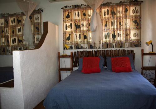 Schlafzimmer mit einem blauen Bett und roten Kissen in der Unterkunft Kiburi Cottage @ Kruger in Marloth Park