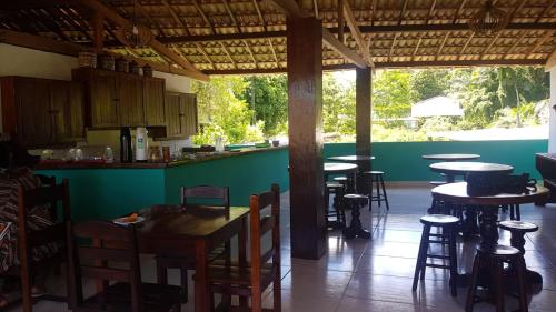 a kitchen with tables and stools in a restaurant at Pousada Iakã Boipeba in Cayru