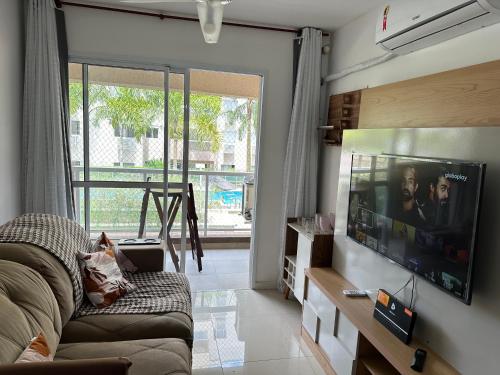 uma sala de estar com um sofá e uma televisão de ecrã plano em Excelente apartamento a 5 minutos da praia e shopping no Rio de Janeiro