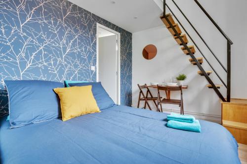 a bedroom with a blue bed with a yellow pillow at Studio avec mezzanine - Wifi - Proche Paris (R8) in Montreuil