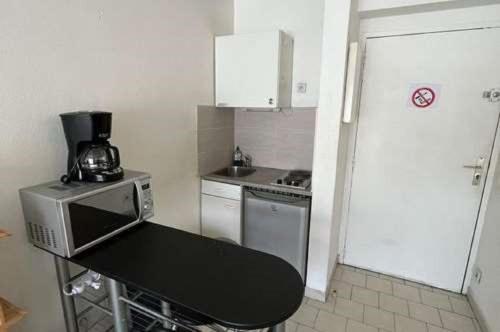 uma pequena cozinha com um micro-ondas e um frigorífico em Beau studio , ensoleillé, Wifi, etage 5 ascenceur em Marselha