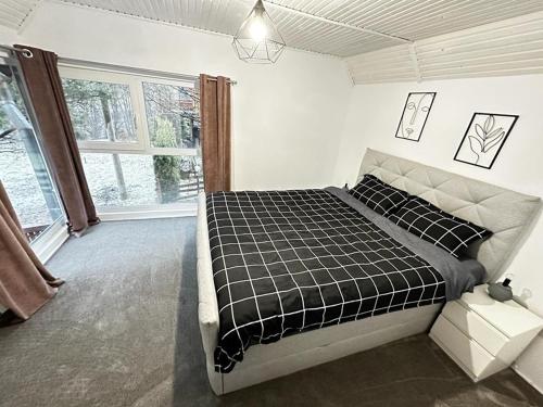 - une chambre avec un lit noir et blanc et une fenêtre dans l'établissement Wood House Valiug, à Văliug