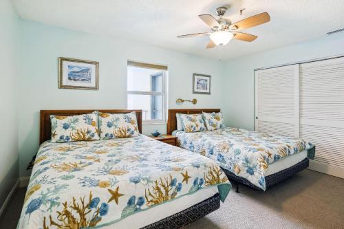 a bedroom with two beds and a ceiling fan at Sea Breeze 401 in St Pete Beach