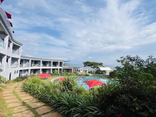 a building with a pool with red umbrellas in front of it at Aquarius Kigo Resort in Kigo