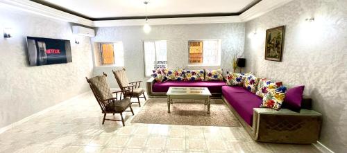 uma sala de estar com um sofá roxo e cadeiras em Appartement centre-ville avec Wifi Fibre Optique em Fez