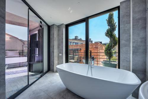 uma banheira na casa de banho com janelas grandes em Mit Hotel Tbilisi em Tbilisi