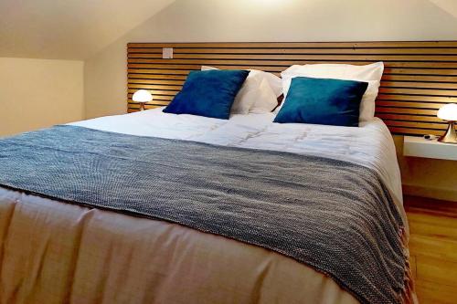 a bedroom with a large bed with blue pillows at The Silent T1 city center JO 2024 PARIS in Chevreuse