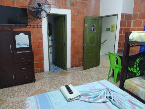 a bedroom with green doors and a bed with a remote control on it at Hospedaje la Viña in El Cerrito