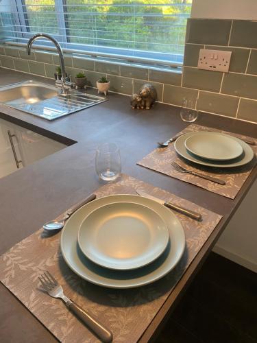 a table with two plates and glasses on a counter at modern 1 bed apartment with car parking in Bitton