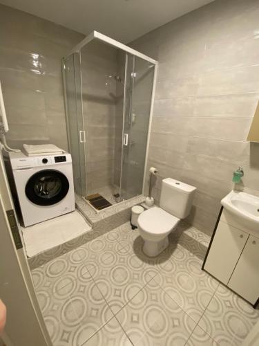 y baño con aseo y lavadora. en Perlos Apartamentai 2A, en Birštonas
