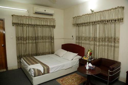Schlafzimmer mit einem Bett, einem Tisch und Vorhängen in der Unterkunft city Homes in Dhaka