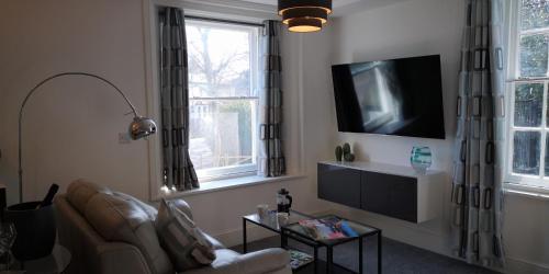 a living room with a couch and a tv at Classy yet cosy and close to Chester City Centre in Chester