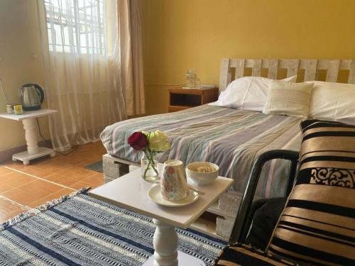 Un dormitorio con una cama y una mesa con flores. en Perfect Travel-Stop Room 3Km From Nanyuki Town - Charell View, en Nanyuki