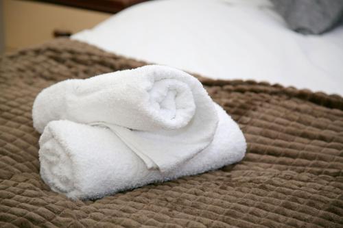 a stack of towels sitting on a bed at Magnolia Lodge in Norwich