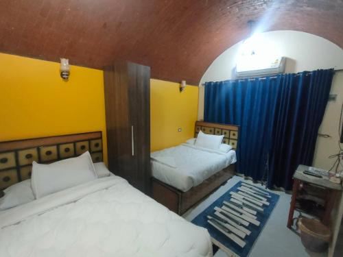 a bedroom with two beds and a blue curtain at Abu simbel Nubian Guest House in Abu Simbel