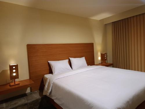 a bedroom with a large white bed with two lamps at Kuta Living by Kamara in Kuta