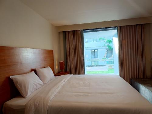 a bedroom with a large bed with a large window at Kuta Living in Kuta