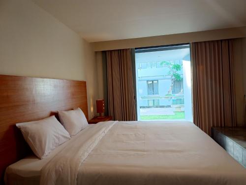 a bedroom with a large bed with a large window at Kuta Living by Kamara in Kuta