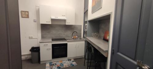 une petite cuisine avec des armoires blanches et un évier dans l'établissement Rue de la coquille, à Béziers