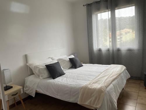 una camera da letto con un grande letto con lenzuola e cuscini bianchi di UCUPPU apartments a Carloforte