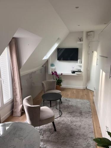a living room with chairs and a table and a tv at Studio R - Paris in Paris