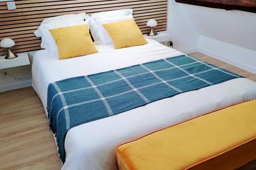 a bedroom with a large bed with two yellow pillows at The Cozy Downtown Duplex in Chevreuse