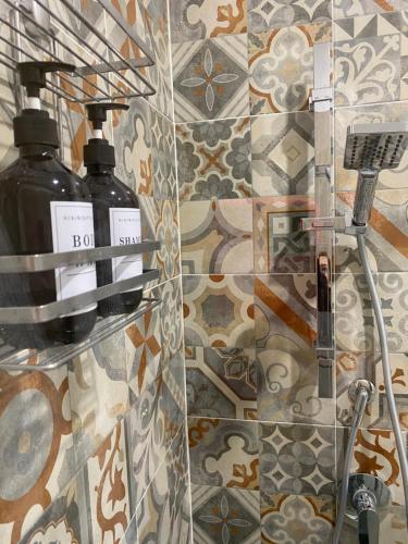 a bathroom with two soap bottles on a tile wall at Luma in Caserta