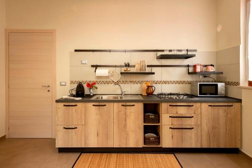 een keuken met een spoelbak en een magnetron bij Appartamento MARISOL Grazioso e vicino al mare in Porto SantʼElpidio