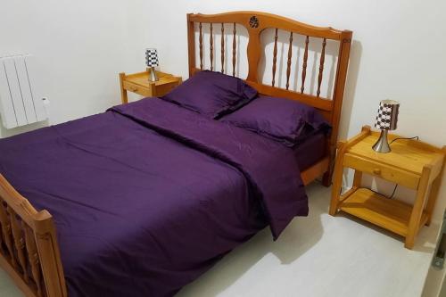 un letto con piumone viola in una camera da letto di Appartement calme bien équipé a Lèves