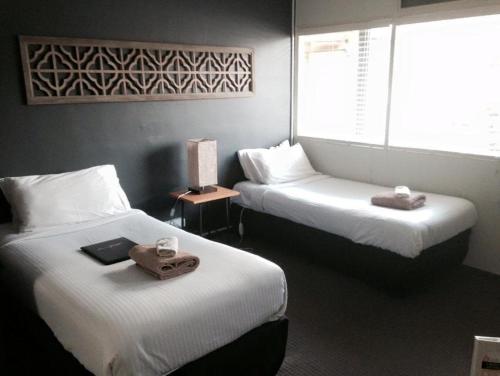a hotel room with two beds with towels on them at Motel Melrose in Mittagong
