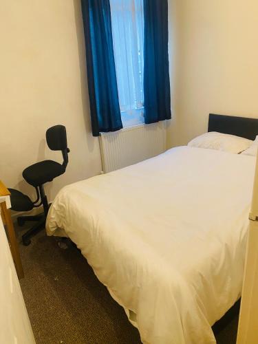 een slaapkamer met een bed, een stoel en een raam bij Portable Single room in Bury