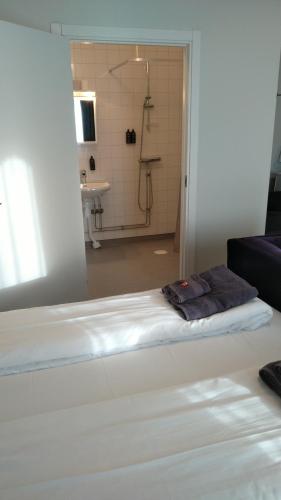 a bed in a room with a bathroom with a shower at Hotel Charlotte / Stella in Uppsala