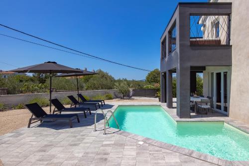 a house with a swimming pool with chairs and an umbrella at Holiday home Nika in Sveti Ivan Dobrinjski