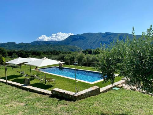 a swimming pool with umbrellas and mountains in the background at Agriturismo Ca' Cristane in Rivoli Veronese